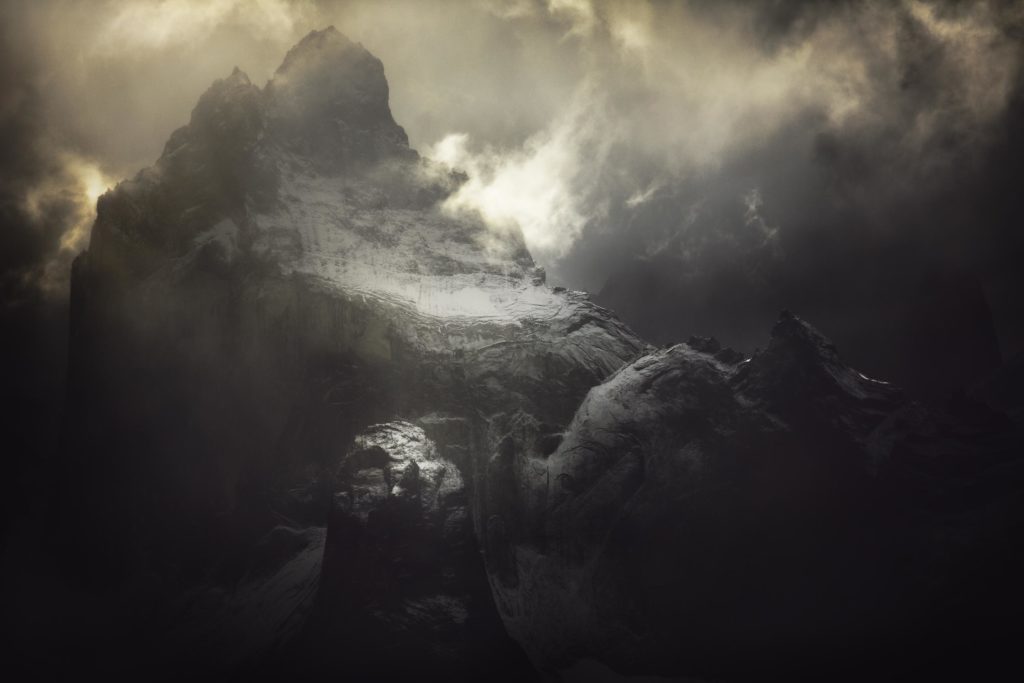 Né de l'Abysse Photographie d’Alexandre Deschaumes – Cuernos del Paine, parc Torres del Paine au Chili. Ambiance mystique et puissante, montagnes sombres éclairées par la lumière dramatique.