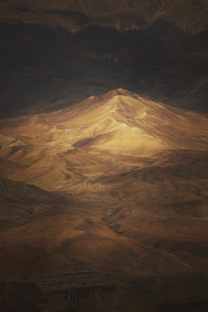 Reliefs dorés du Mustang au Népal éclairés par une lumière dramatique, ambiance désertique et science-fiction